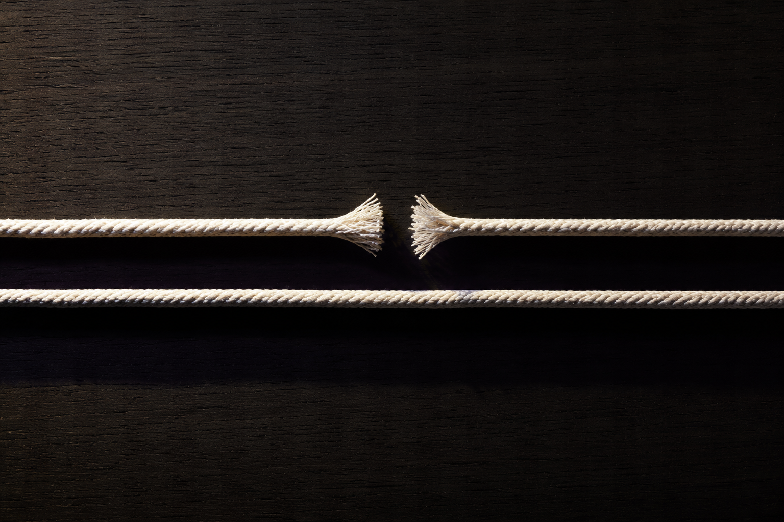 Overhead editorial photograph of two parallel ropes on dark wood, the upper one severed at the centre and the lower one running unbroken, illustrating browser-side collection breaking where server-side collection holds.